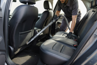 Detailing professional vacuuming and cleaning seats inside a real passenger car