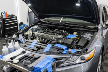 Open engine bay of a real car prepared for careful professional cleaning